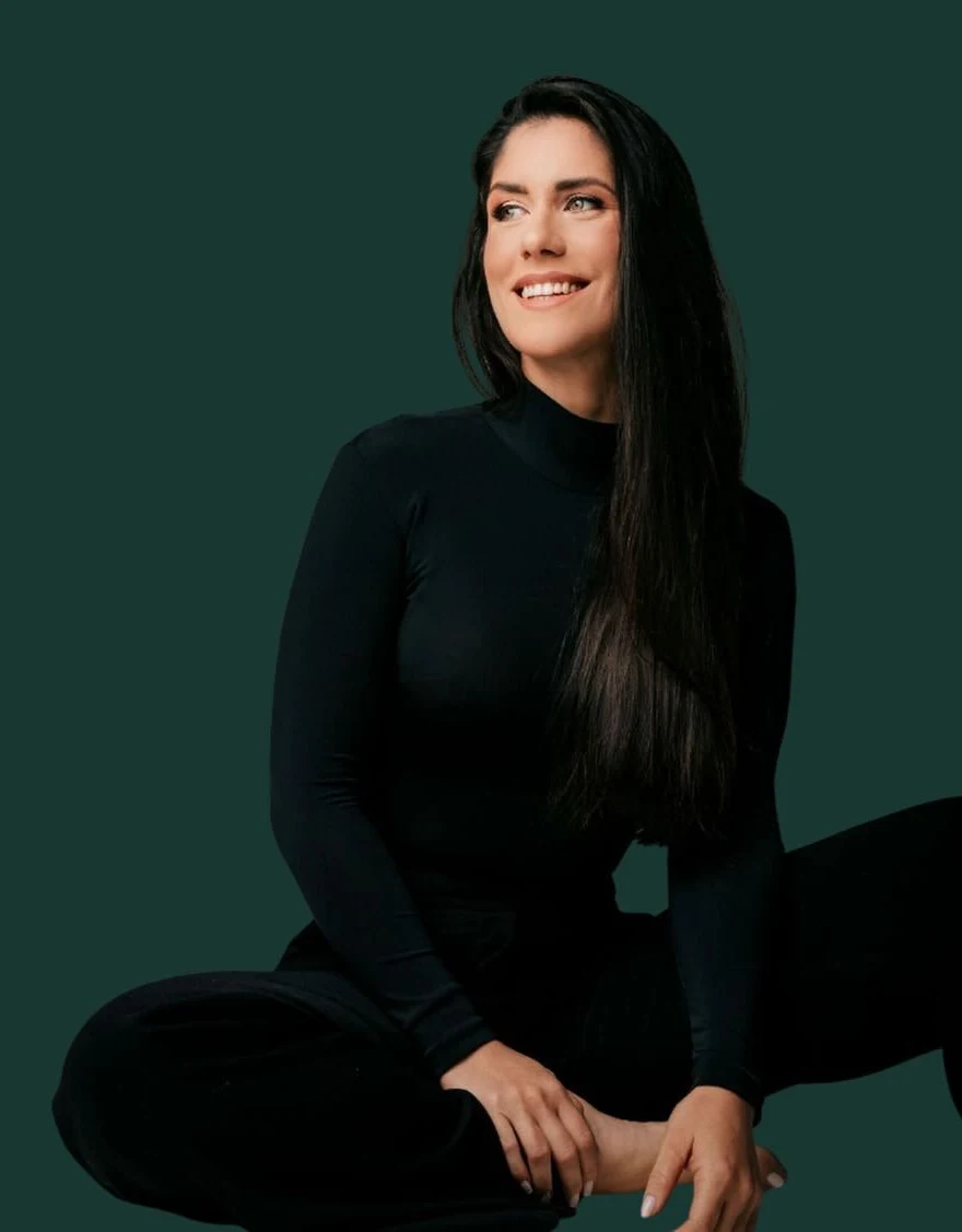 Marcella Maia sentada, sorrindo e olhando para o lado